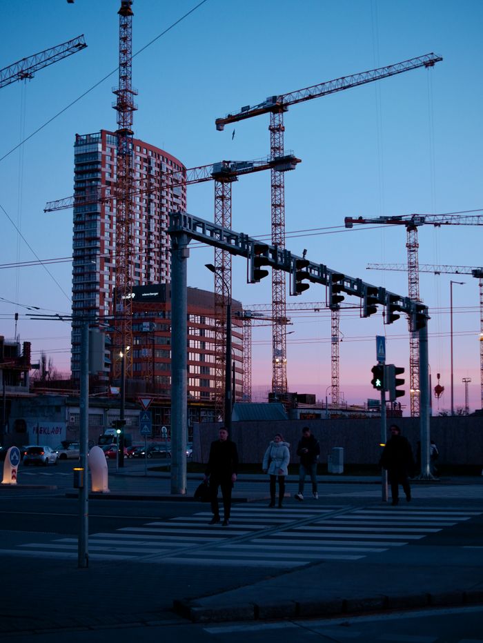 A cityscape view of Bratislava's modern architecture and construction cranes at sunset.