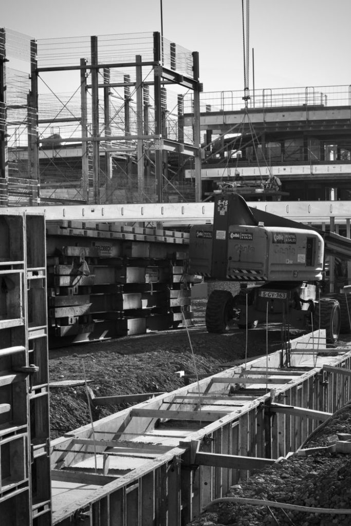 Monochrome image of a construction site featuring heavy machinery and scaffolding.